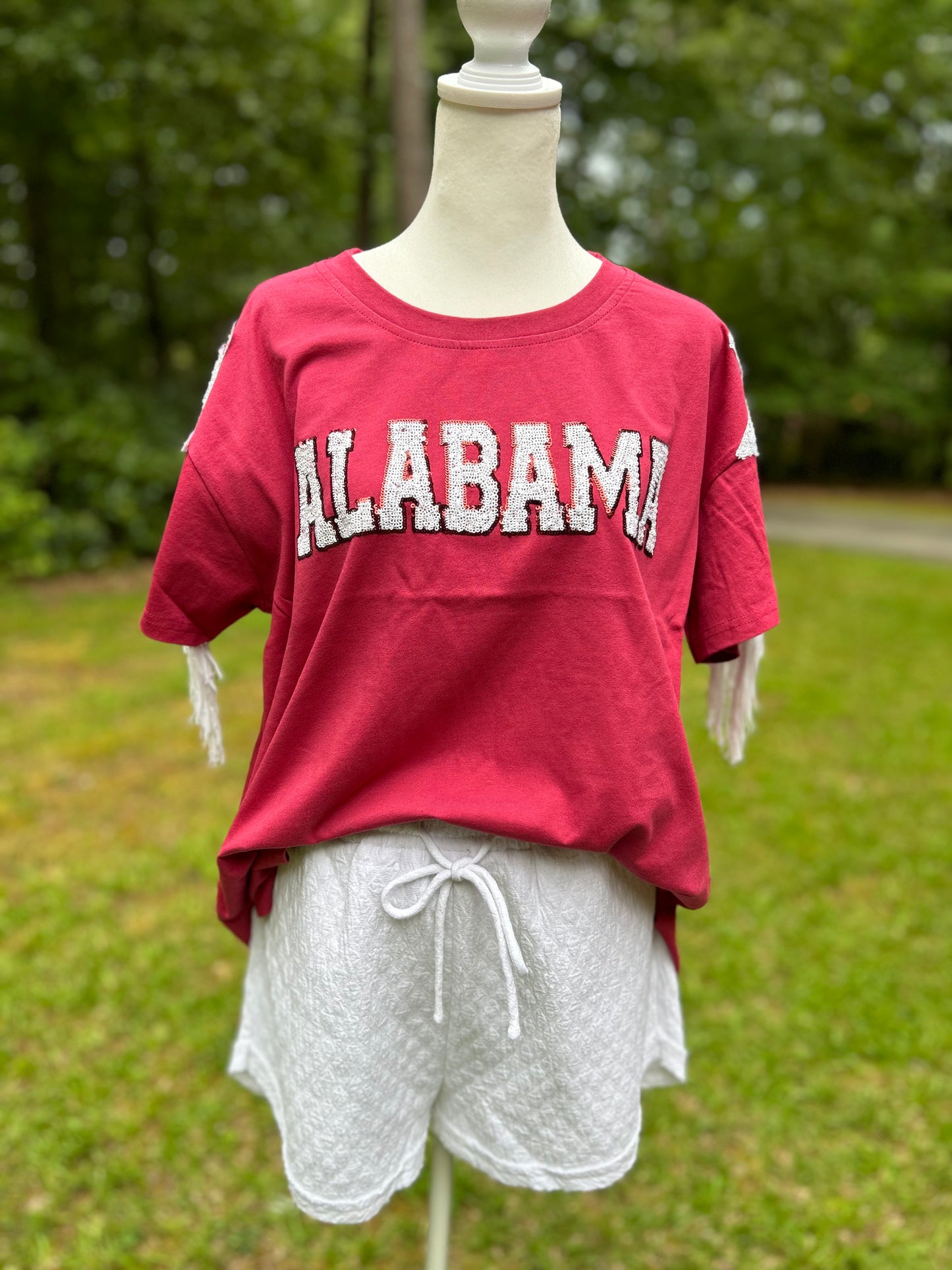 Crimson Alabama gameday shirt. White sequins spell out Alabama. Star sequin and fringe detail on the sleeves.