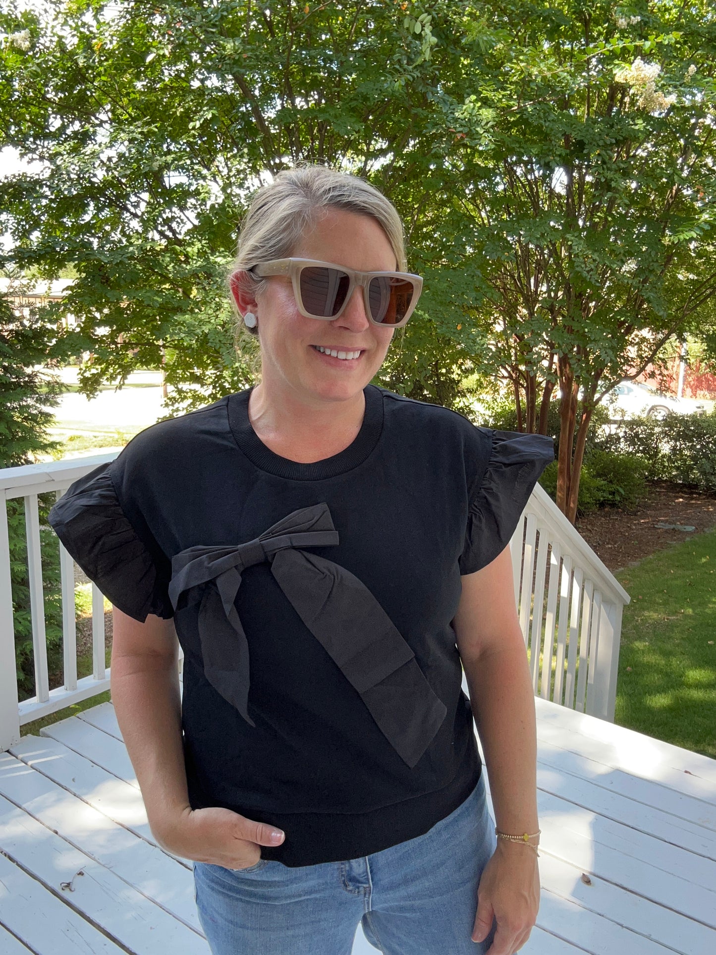 Short sleeve black top with ruffle sleeves and bow detail.