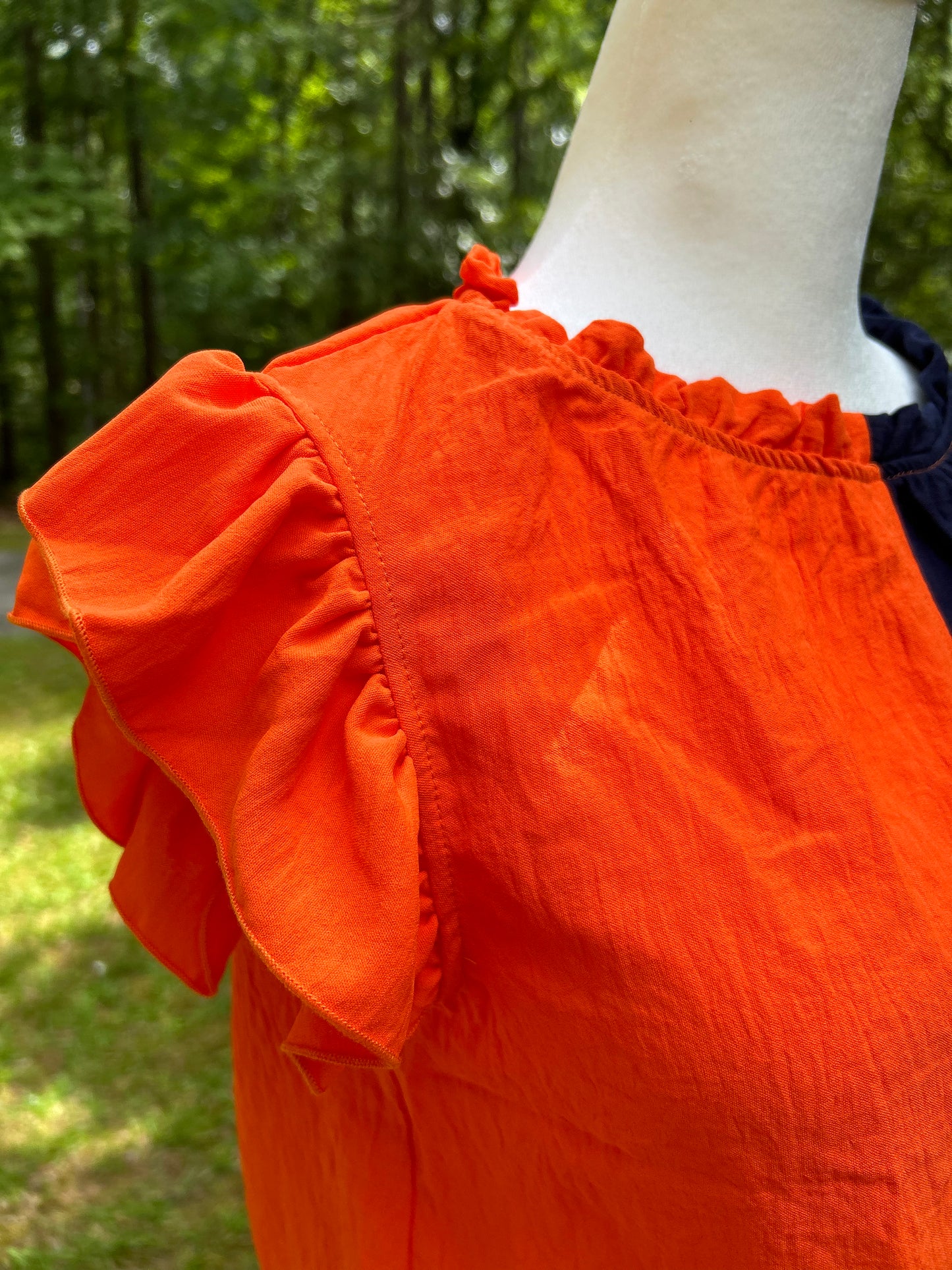 Colorblock top in orange and navy with ruffle details.