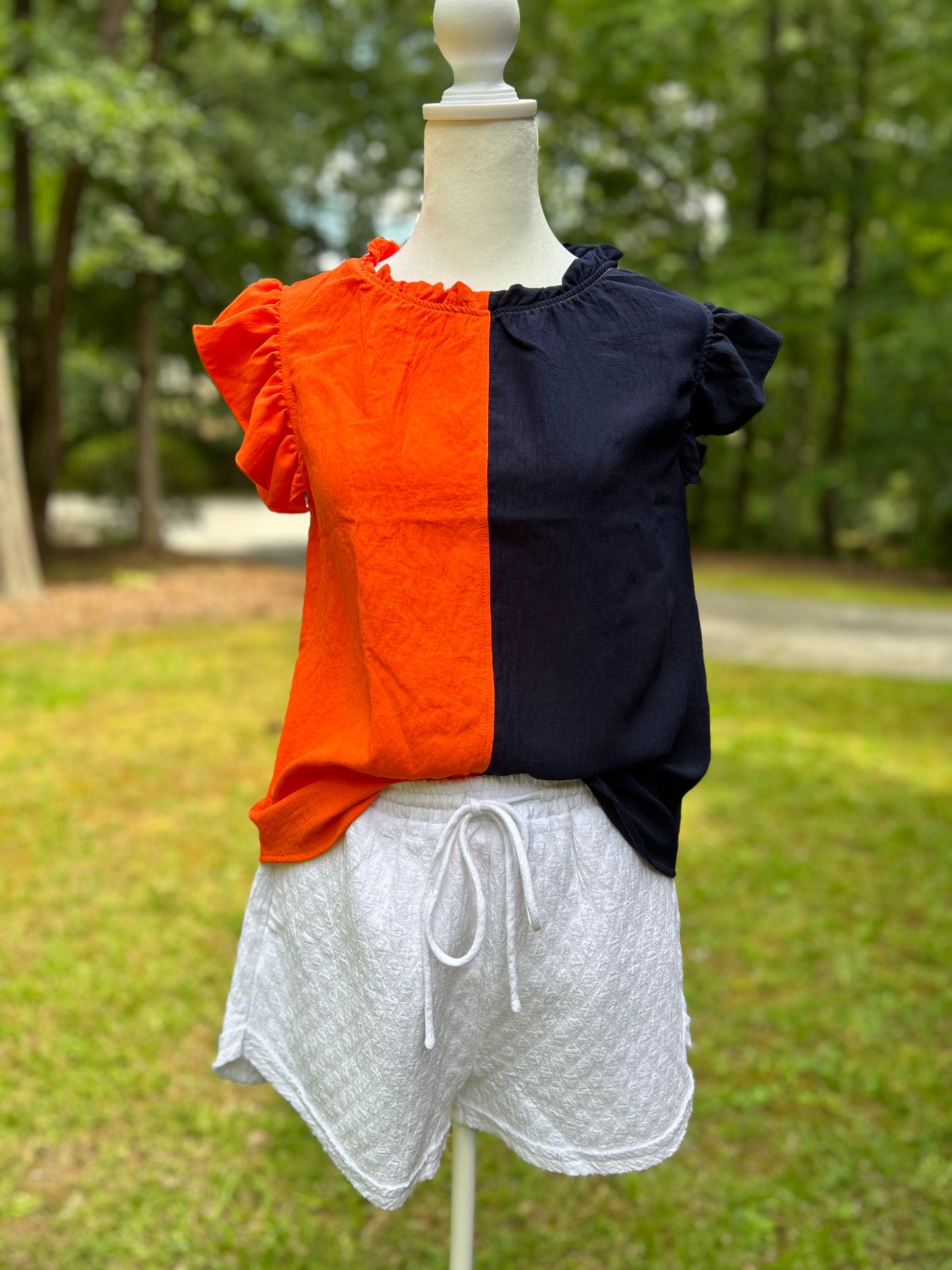 Colorblock top in orange and navy with ruffle neckline and sleeves.
