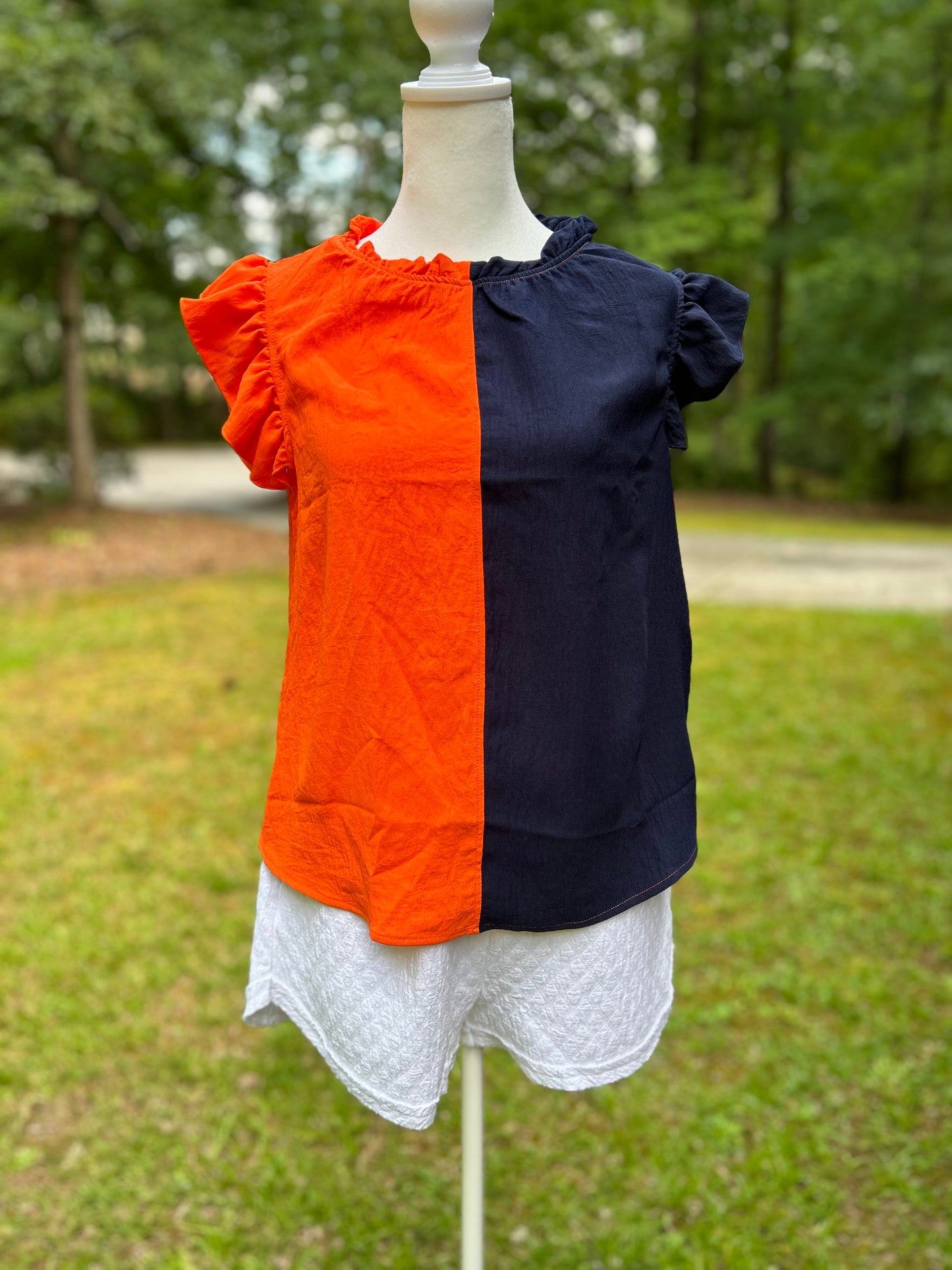 Colorblock top in orange and navy with ruffle sleeves and neck.