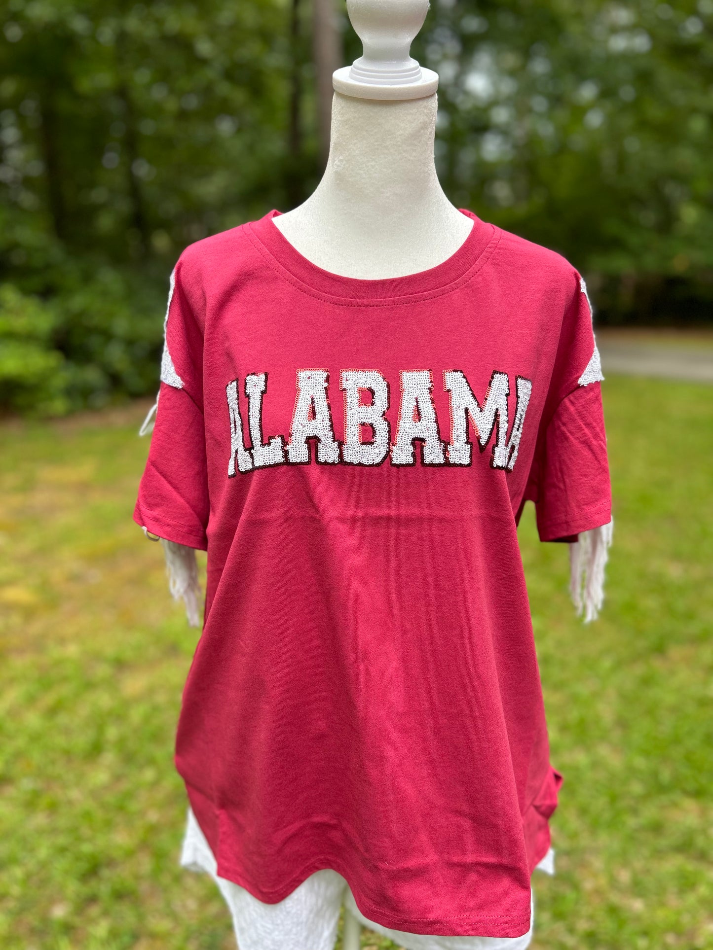 Sequin letters in white spelling out Alabame. Sequin star and fringe detail on the sleeves.