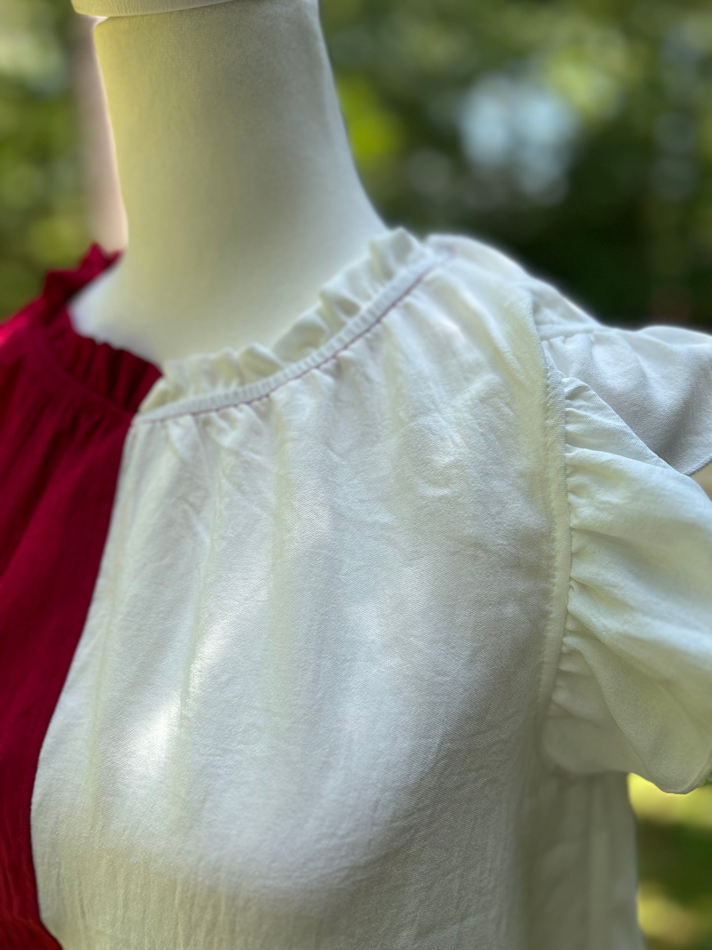 White and crimson colorblock top with ruffle details on the sleeves and neckline.