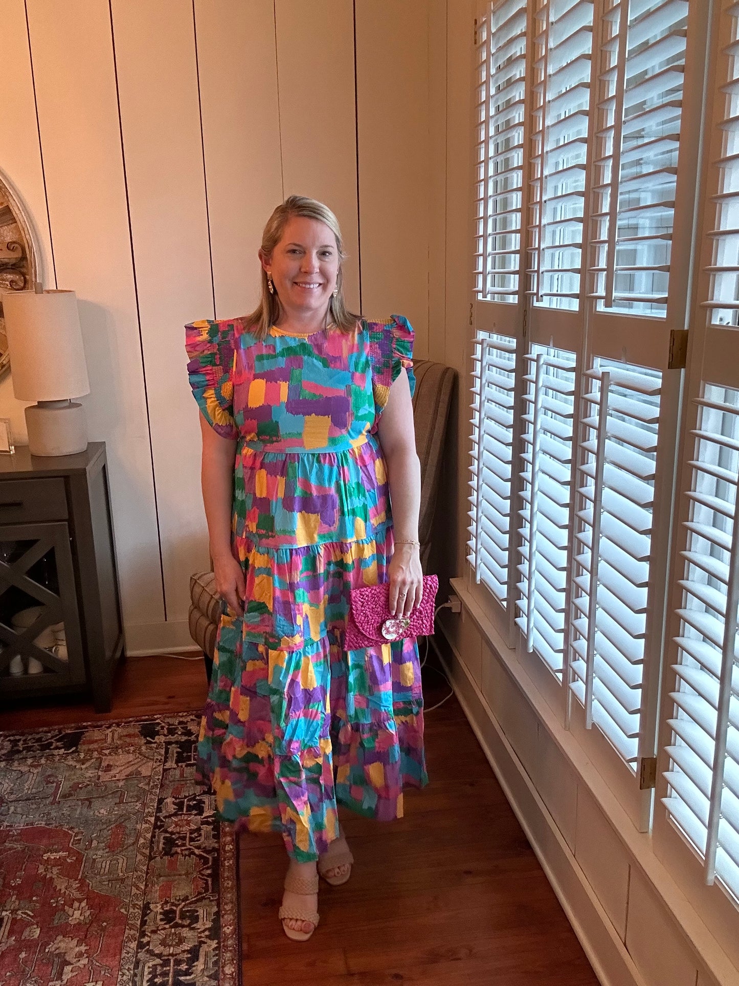 Long dress with flutter sleeveless sleeves.  Flutter goes over the shoulder. Abstract block print in bright pink, purple, golden yellow, turquoise blue and green. Smocking on the upper back for stretchy fit. Seam around waist and tiered seams on the way down for a flowy bottom.