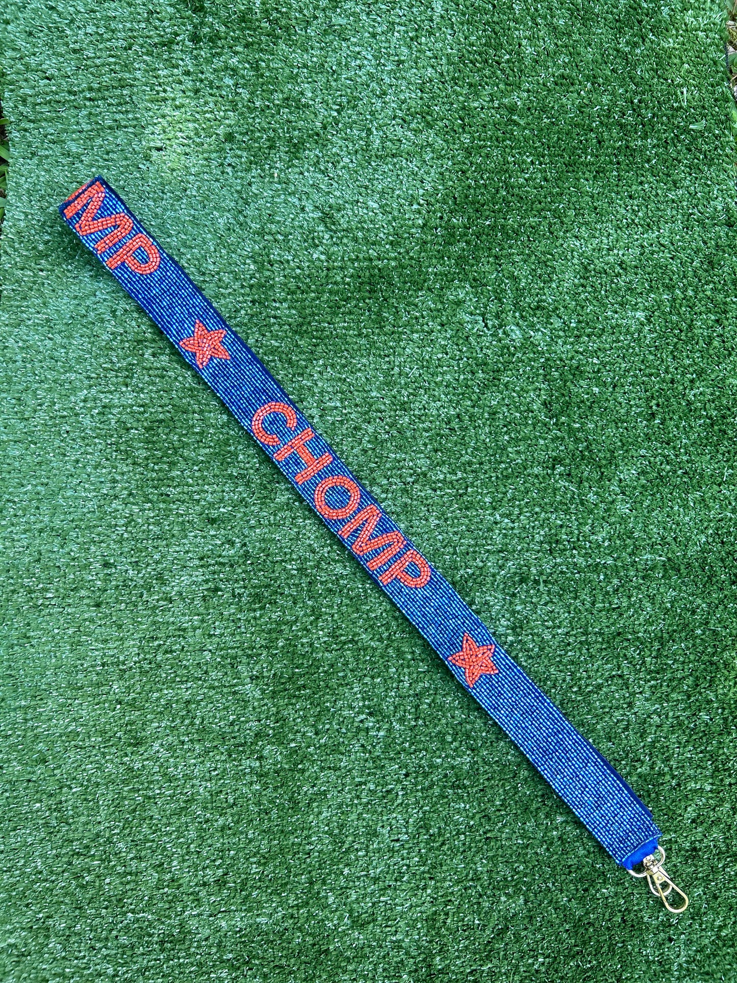 Beaded gameday strap for stadium bags. Blue background with orange beaded letters spelling out Chomp.