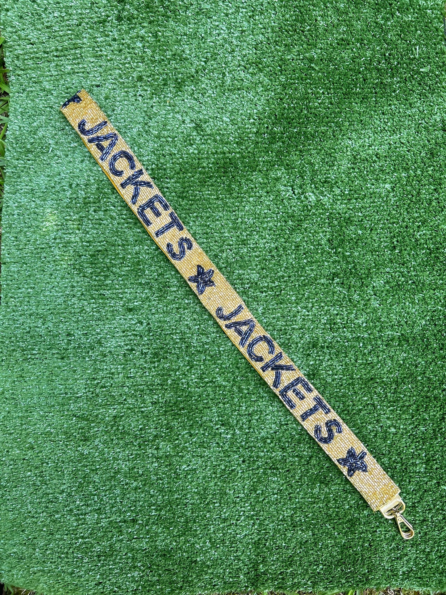 Beaded gameday strap. Gold background with navy blue letters spelling Jackets and a navy blue star.
