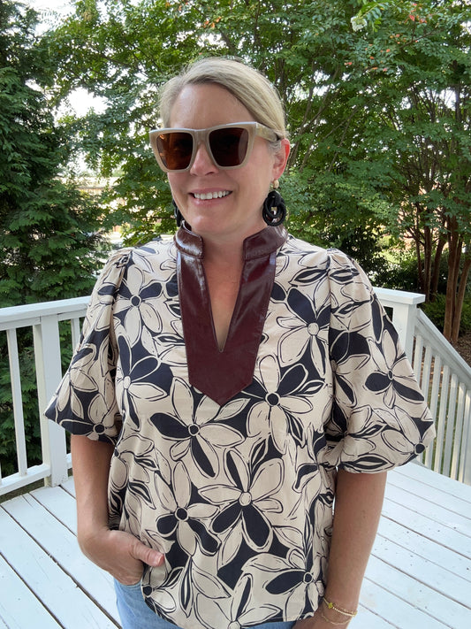 Flower print top in black and cream with a maroon faux leather trim on the v-neck collar. Puff sleeves.