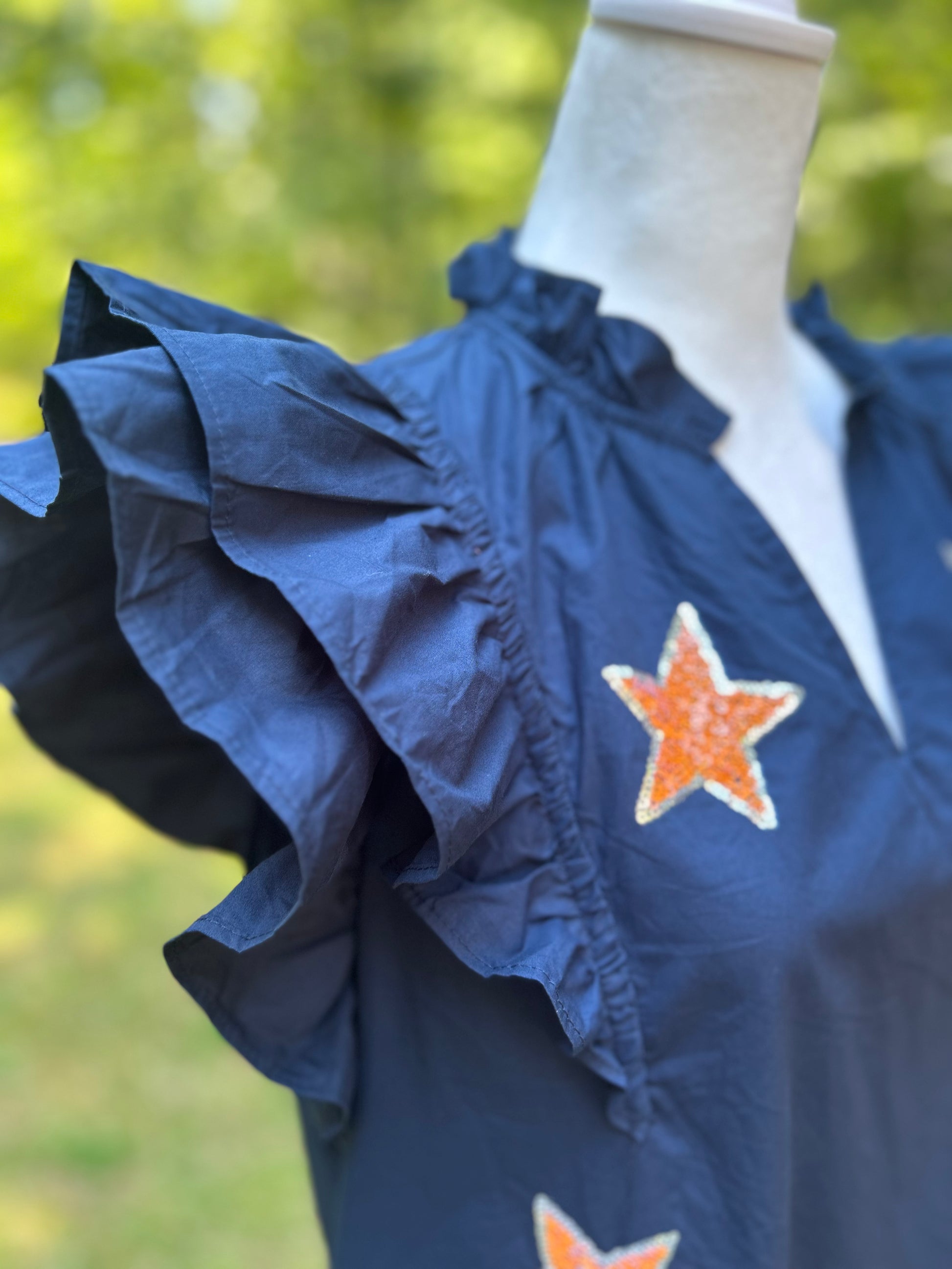 Sequin stars over a navy ruffled dress with pockets. 
