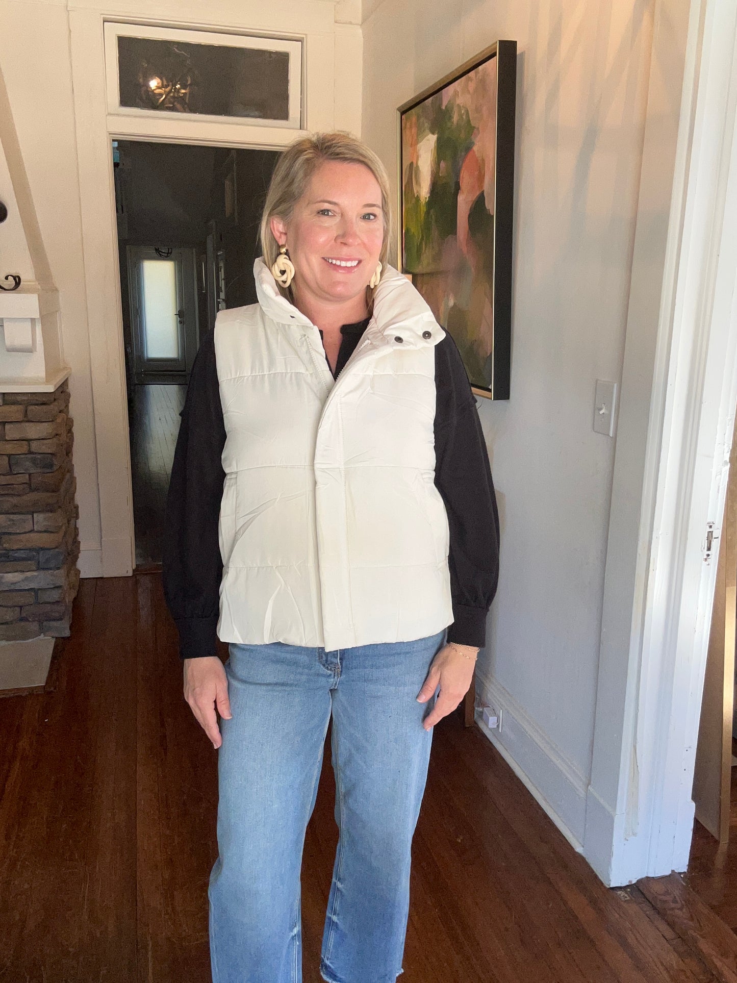 Ivory puffer vest with a high neck and zippered closure. 