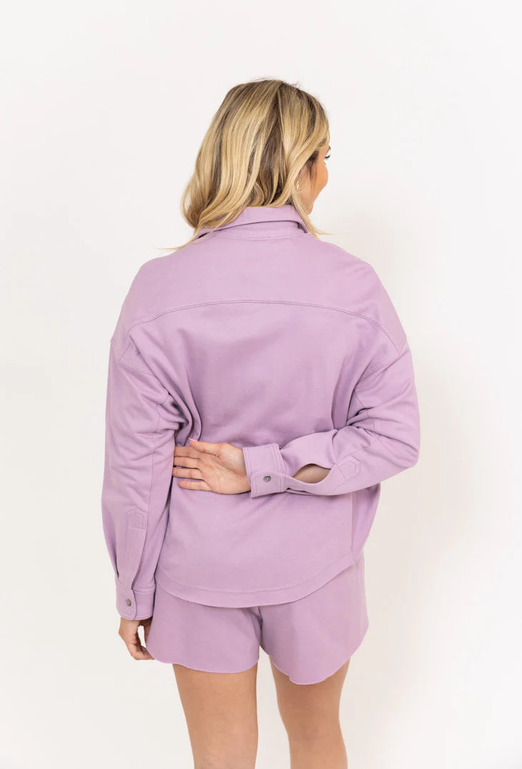 Woman wearing a matching lavender shirt and shorts set on a white background
