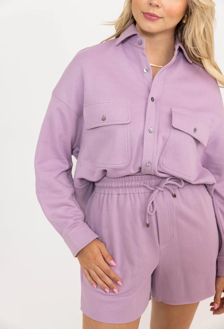 Woman wearing a matching lavender shirt and shorts set on a white background