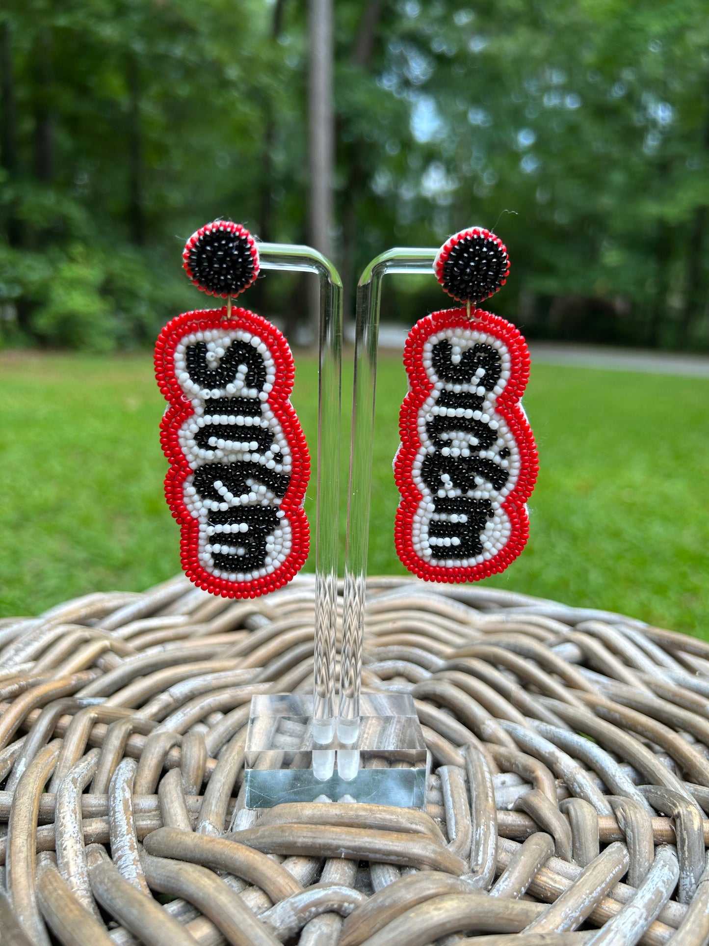 Lightweight, beaded earrings that spell Sic'em in black letters surrounded by white and red borders. The beaded stud part is black beaded with a red bead border.